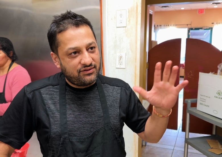 A man in an apron stands in a restaurant. 